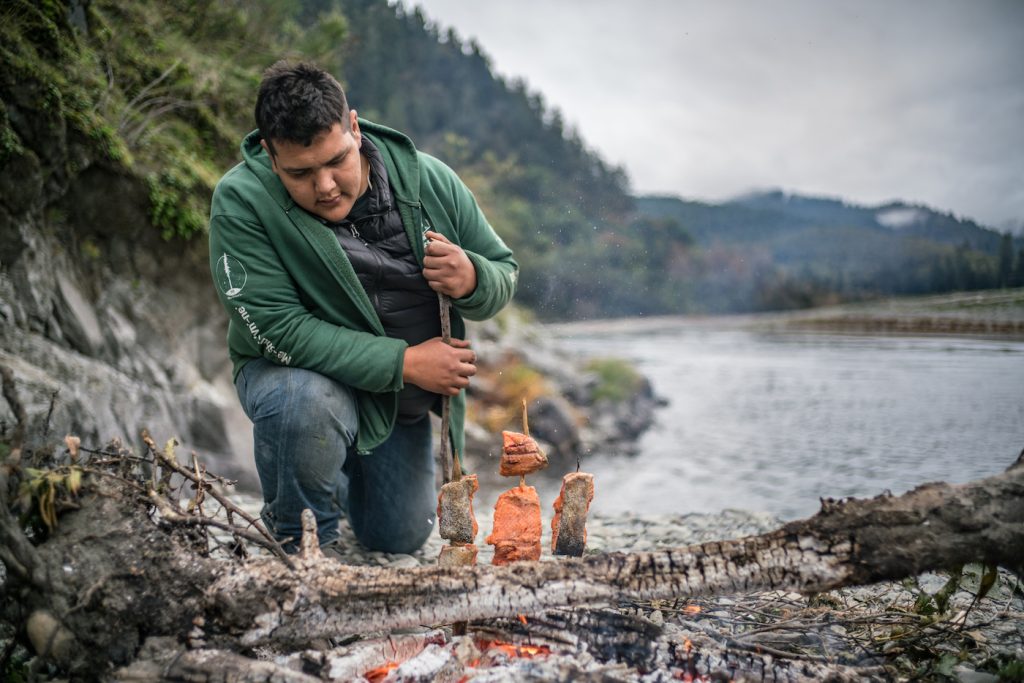 Sammy Gensaw (Yurok) of the youth group The Ancestral Guard prepares salmon in a traditional fashion on the Klamath River in the heart of the Yurok Reservation (northern California).