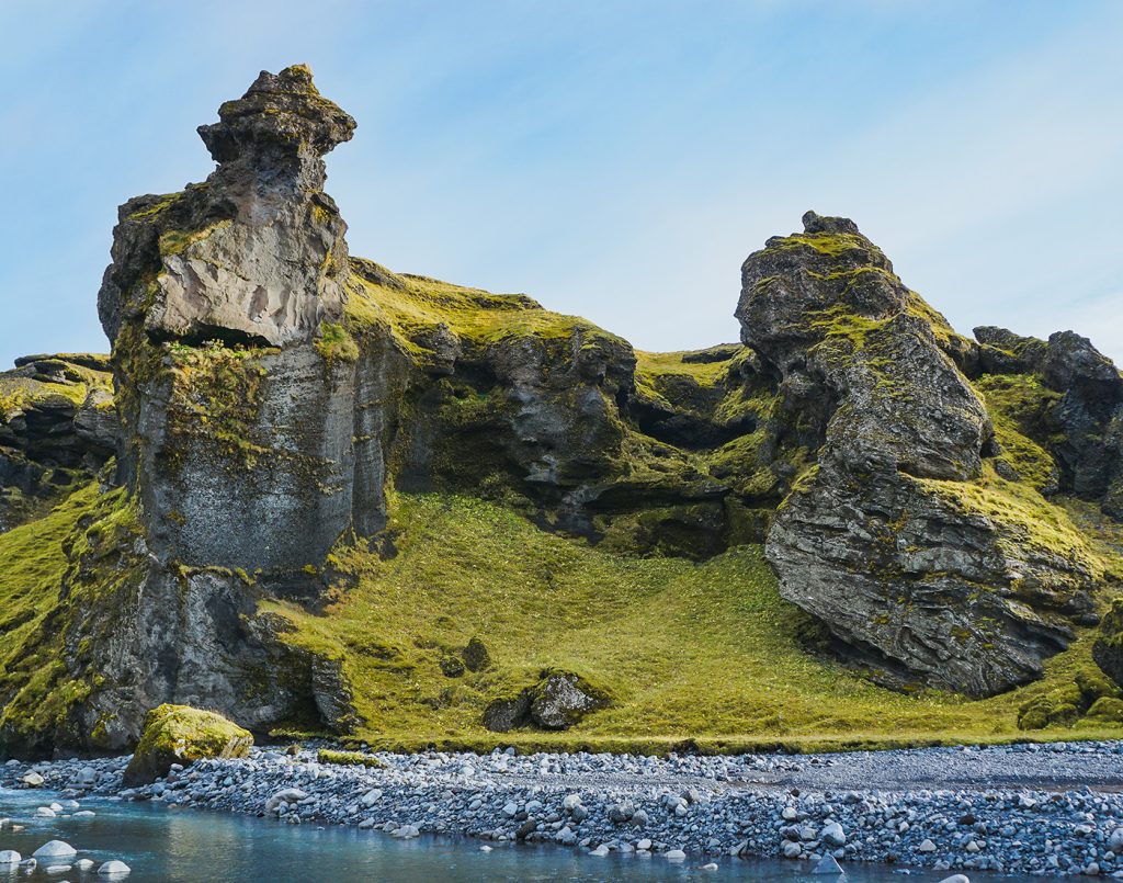 Rocks covered in moss tumble toward a pebble-strewn creek.