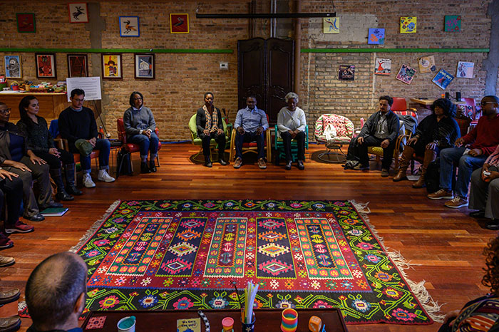 Spiritual Ecology and Culture participants sit in a large circle in a colorful room.