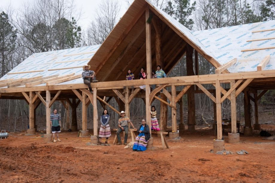 Members of the Indigenous Maskoke community stand on the site of their Timber-Framed Community Center in the Ekvn-Yefolecv ecovillage.
