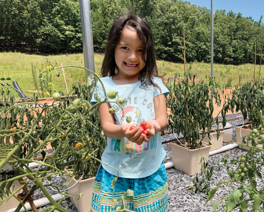 A Maskoke child holds tomatoes grown in the Ecovillage greenhouses.