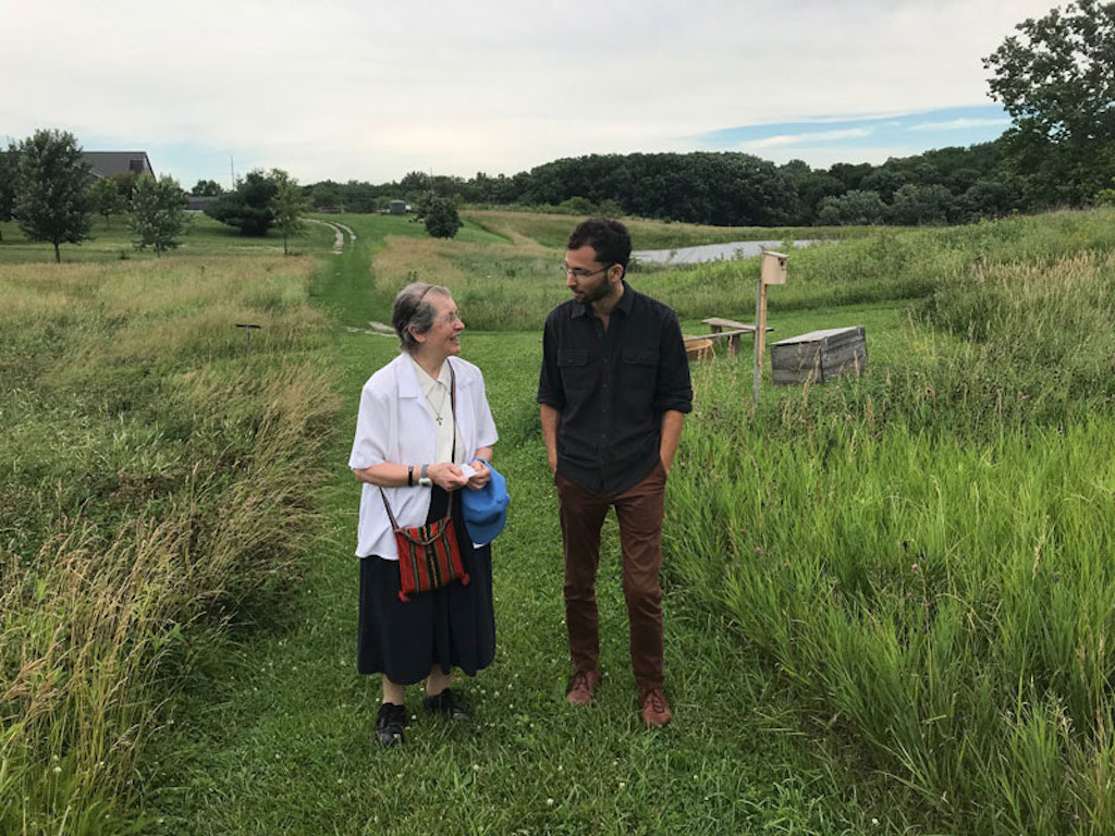 Two people standing in a green field.