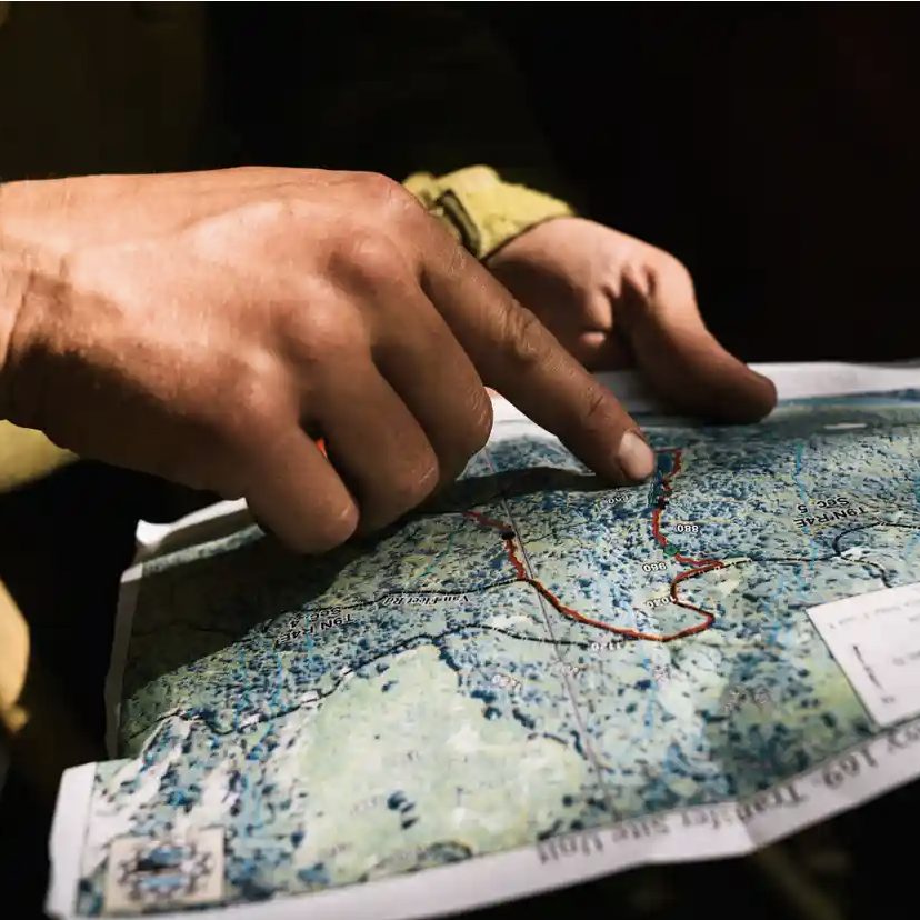 Close up of Native hands outlining a red line on a map.
